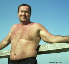 hairyman leaning on fence beach driftwoo